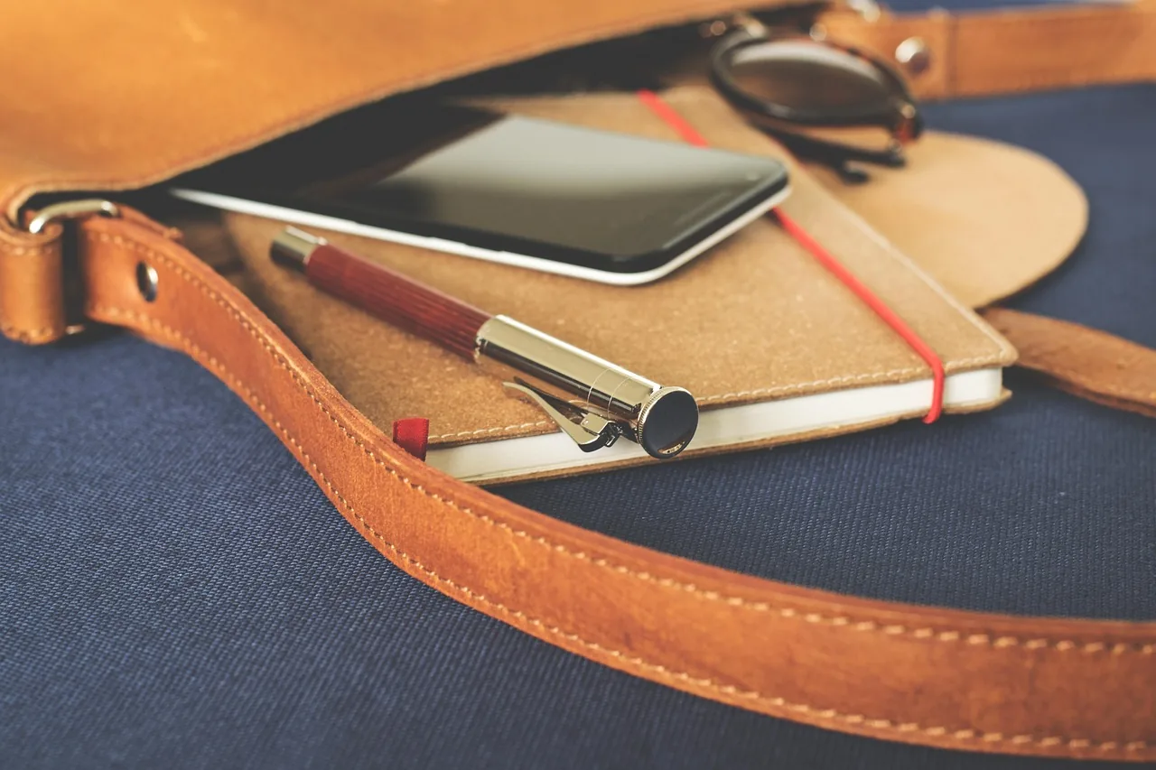 Notebook, pen and phone on a satchel, for organizing your services