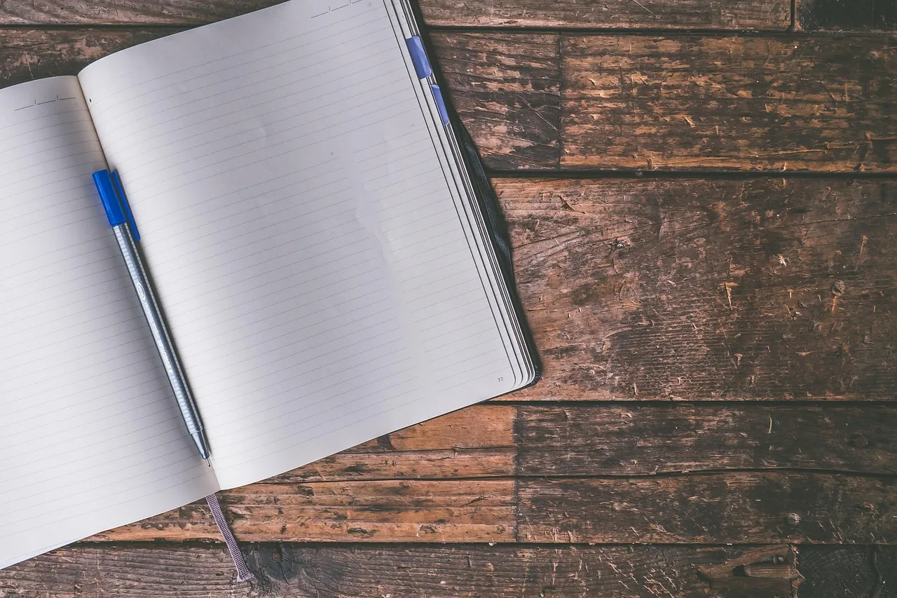 Open notebook with blank pages and a pen on a work desk