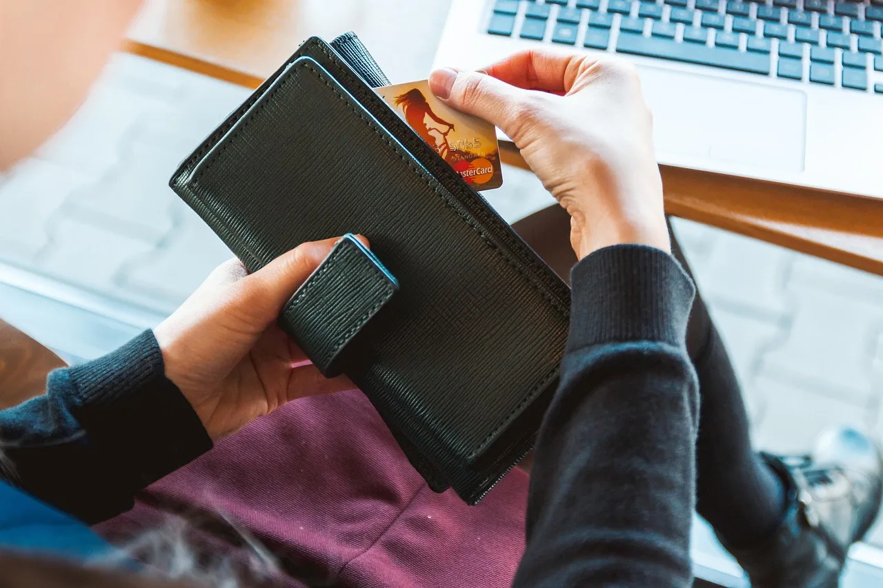 Person holding a wallet in front of a laptop