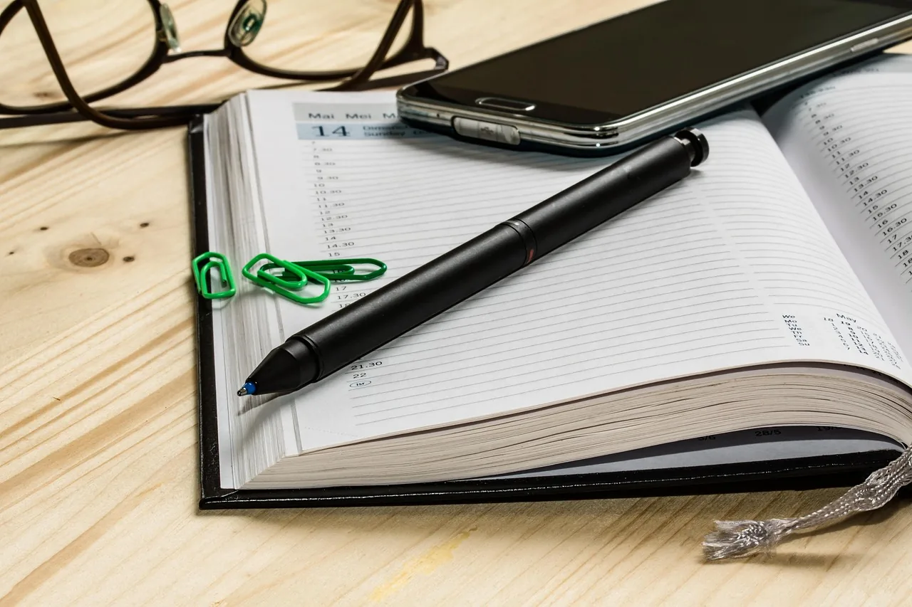 Open notebook, pen and paper clip on a table